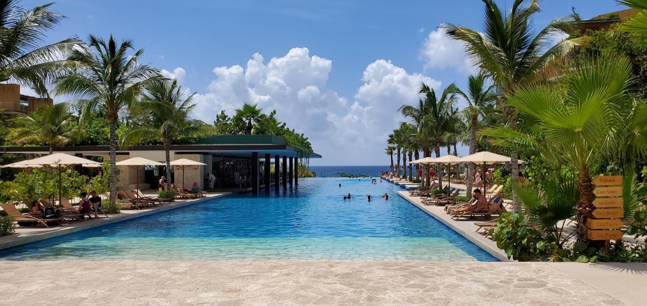 Infinity pool at Hotel Xcaret Mexico framed by tall palms and opening toward the Caribbean Sea